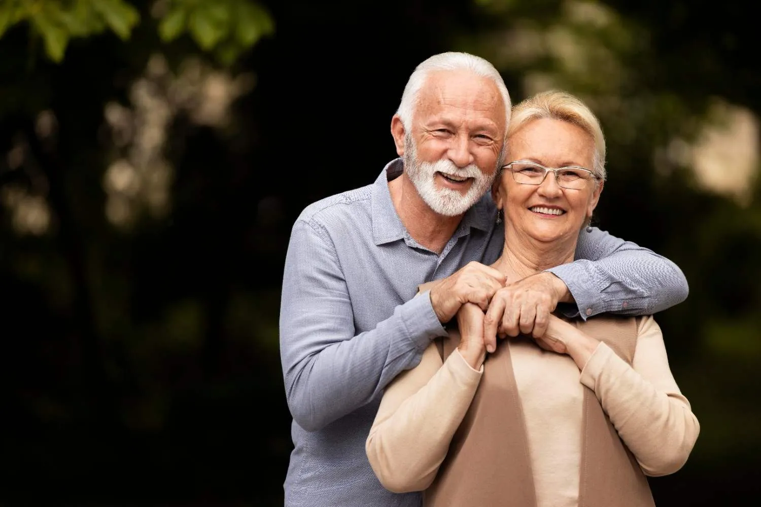 A smiling older couple standing together outside
