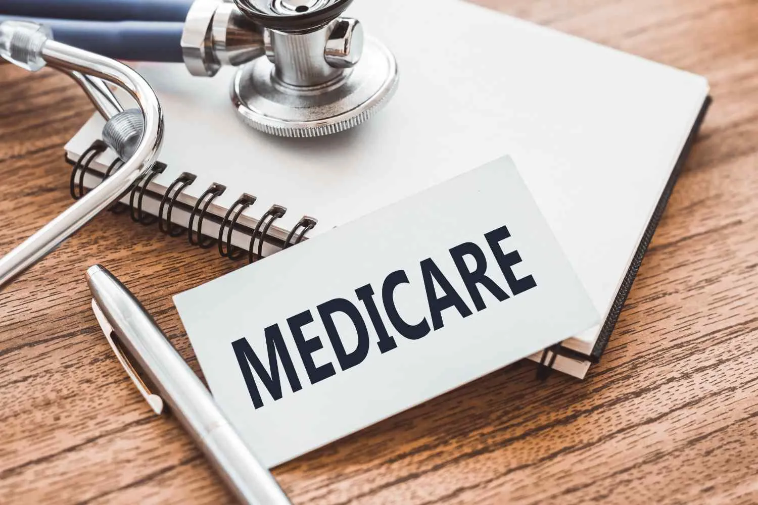 A card marked Medicare resting on a notebook beside a stethoscope