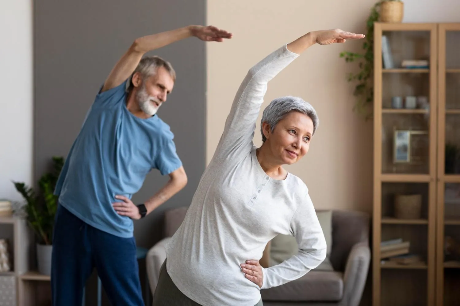 An older couple stretching together in their living room